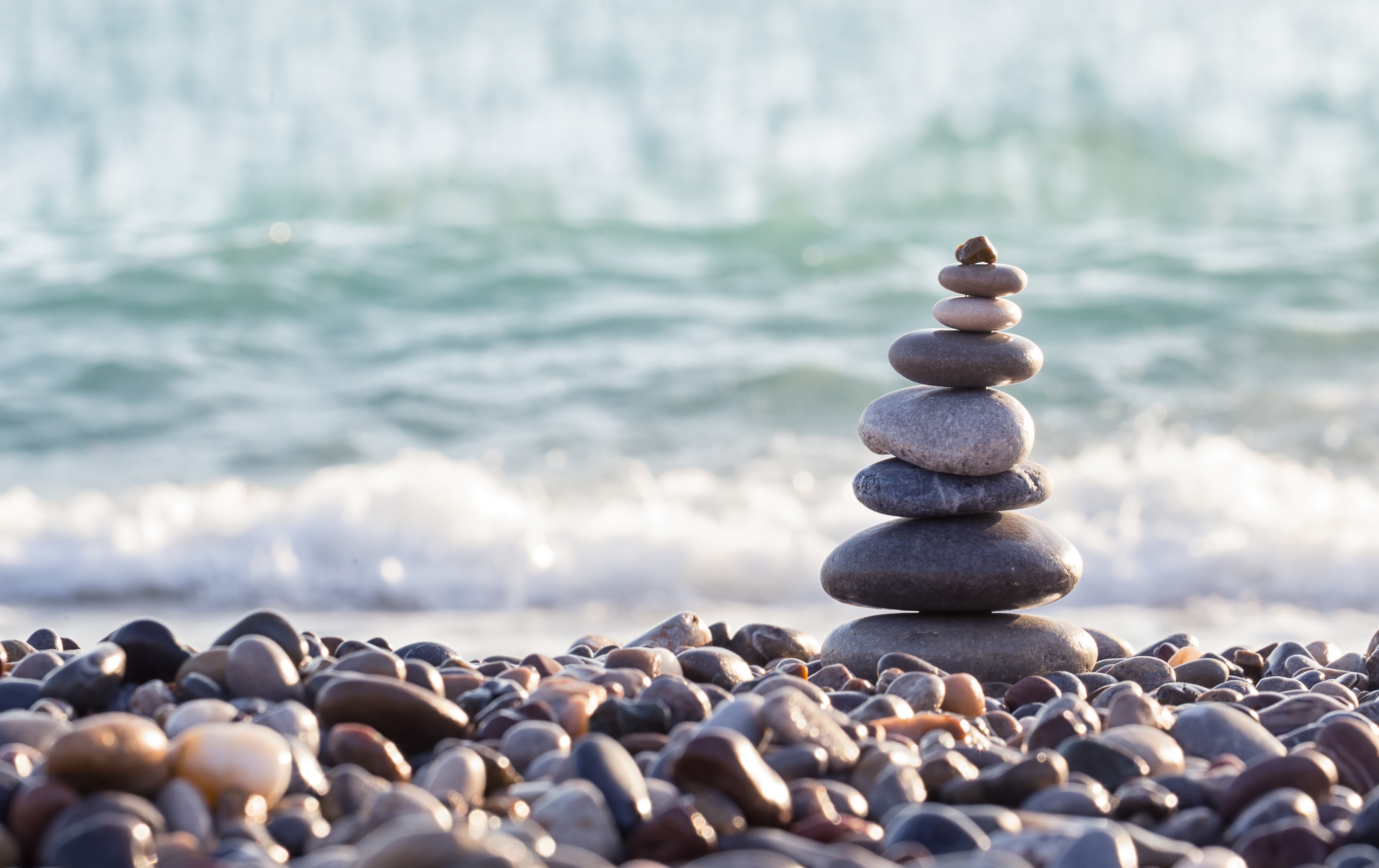 Pyramid of sea stones on pebbles of the sea shore | Riviera Recovery