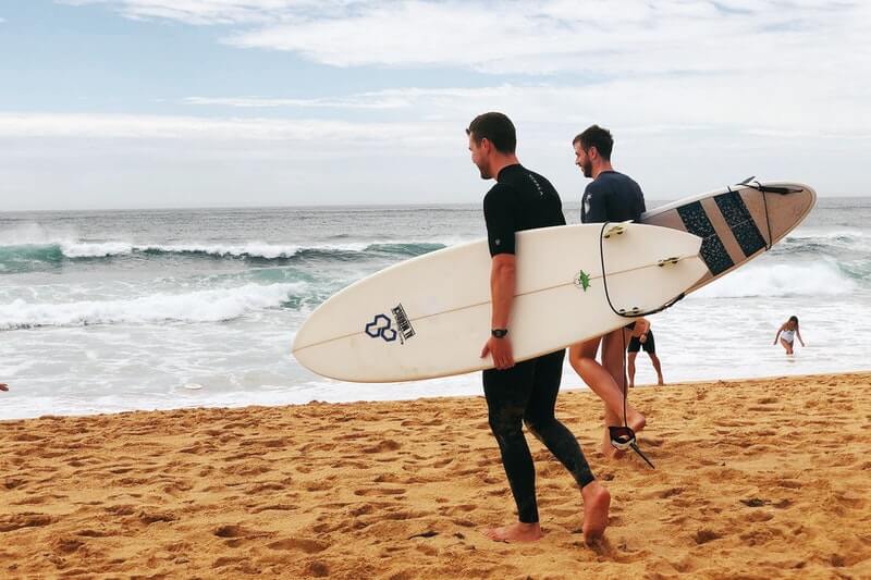 two men carrying surfboards near sea shore, stages of recovery the wall, the wall stage of recovery, addiction recovery center