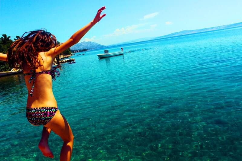 woman wearing bikini jumping into the ocean, addictions and recovery relapse, addiction recovery relapse prevention