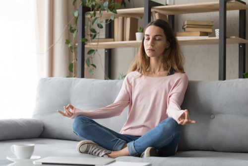 woman meditating on couch to help relieve some induced stress