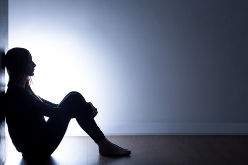 silhouette of a person sitting on the floor being depressed